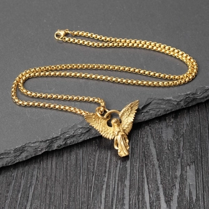 Macro shot of gold angel wing pendant on box chain over rustic slate and dark wood