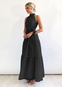 Detail of black halter maxi dress showing textured plaid jacquard fabric and waist tie