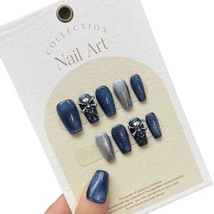Deep blue cat-eye press-on nails set featuring glitter finish and silver skull charms