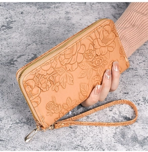 Close-up of a long tan leather wallet for women with 3D rose floral embossing and a wrist strap