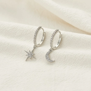Detailed view of silver hoop earrings featuring micro-pave moon and star charms with zircons