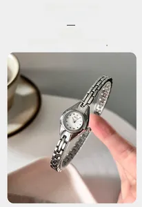 Gros plan d'une montre bracelet argentée avec cadran blanc rond et index en cristal