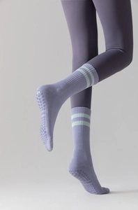 Detail of purple non-slip yoga socks with green stripes and grip texture on the sole