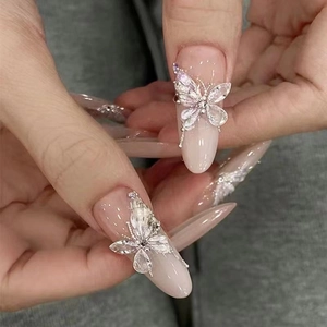 Detailed close-up of 3D butterfly zircon nail charms on long almond press-on nails