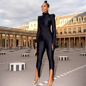 Detail of black mock neck long sleeve jumpsuit with shoulder pads and stirrup hem design