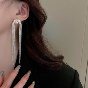 Close-up of model wearing silver tassel earrings with pearl stud and long metal chains