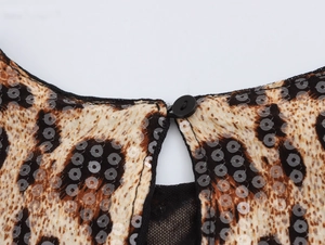 Détails de la blouse léopard avec paillettes, bouton au dos et empiècement en maille noire