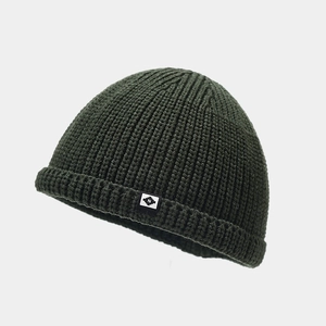 Détail d'un bonnet docker en maille côtelée vert foncé avec étiquette blanche lettre N