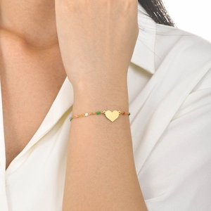 Detailed view of a gold heart charm bracelet with colorful beads worn on a wrist