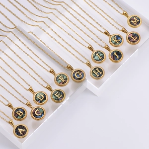 Gold stainless steel alphabet necklaces with shell inlay on tiered acrylic stands