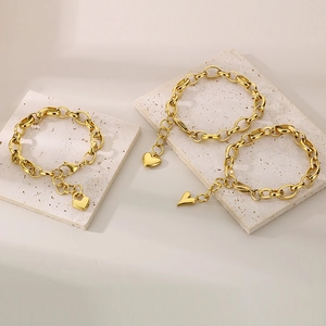 Detailed view of three 18K gold plated chain bracelets with heart charms on stone