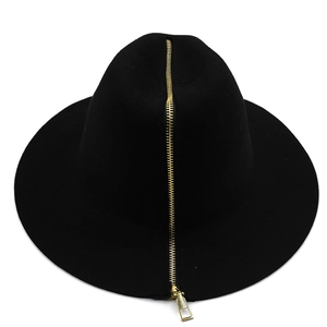 Detail of a black wool bucket hat featuring a decorative gold zipper on the crown