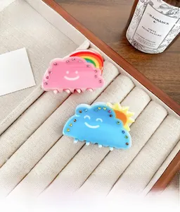 Detail of cloud-shaped acrylic hair claws with rhinestones and smiling face patterns