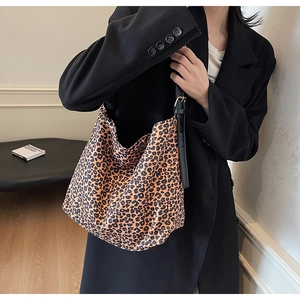 Close-up of leopard print canvas bag with adjustable black shoulder strap and metal buckle
