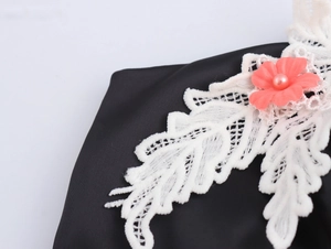 Detail von 3D-Korallenblume mit Perle und weißer Spitzen-Applikation auf schwarzem Top