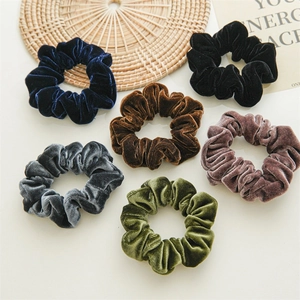 Detailed flat lay of six colorful velvet hair scrunchies on a minimalist white table