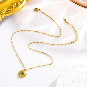 Close-up of golden stainless steel necklace with turquoise pendant and embossed details