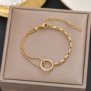Macro detail of 18k gold plated stainless steel bracelet with geometric rings on jewelry box