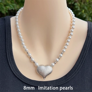 Detail of 8mm imitation pearls necklace with silver hammer textured heart pendant