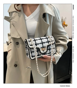 Dettaglio borsa in tweed bianco e nero con chiusura a scatto dorata e tracolla a catena