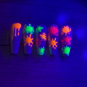 UV-reactive neon orange and green drip patterns on long stiletto press-on nails