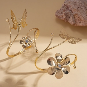 Elegant gold open arm cuff bracelet with sparkling crystal flowers and butterfly charms
