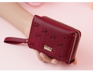 Detailed embroidery of elegant floral patterns on a burgundy short zip leather wallet