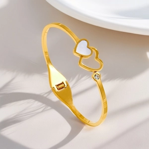 Detail of 18K gold plated steel bracelet featuring a mother of pearl heart and a rhinestone