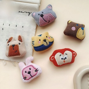 Detailed embroidery on colorful plush animal pins including tiger, bear, and bunny