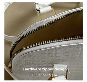 Close-up of golden metal zipper and crocodile embossed leather texture on shell bag