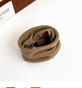 Detailed view of a soft brown velvet scrunchie on a clean white surface with natural light