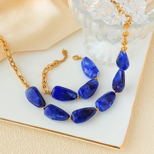Macro detail of dark blue marble stone necklace and golden stainless steel link chain
