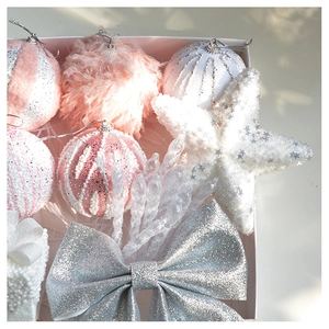 Close-up of pink plush Christmas balls, silver glitter bows, and stars in a gift box