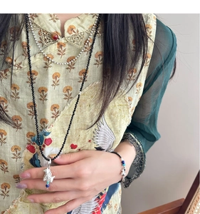 Detailed view of beaded necklace with mythical beast pendant on embroidered silk apparel
