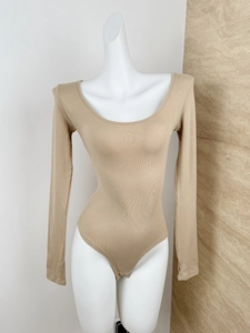Detail of beige ribbed knit bodysuit showing the snap-button crotch and slim fit texture