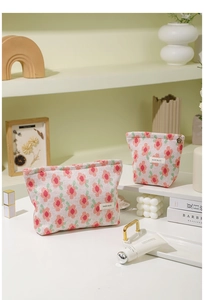 Close-up of two knit floral cosmetic bags with H&R BAG labels and metal zipper details
