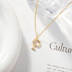 Detailed close-up of golden letter P pendant with zircon flower on a refined O-chain