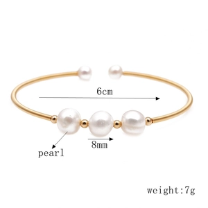 Detailed view of open gold bracelet featuring 8mm white pearls and 6cm diameter