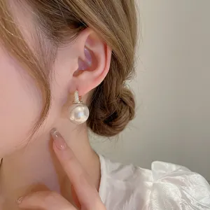Élégantes boucles d'oreilles dorées avec grandes perles rondes et zircons brillants