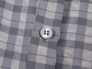 Détail macro de la robe à carreaux grise montrant le sergé et le bouton à quatre trous