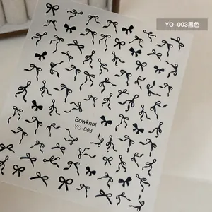 Close-up of YO-003 nail stickers featuring various black bowknot patterns on gray background