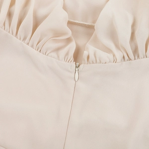 Detail of invisible zipper and elegant pleated texture on a beige chiffon dress