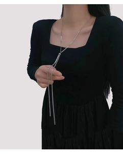 Detail of adjustable silver Y-necklace with snake chain and sliding bead on black dress
