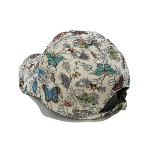 Detail of beige baseball cap with colorful butterfly embroidery and woven fabric texture