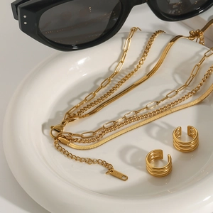 Three-layer gold stainless steel necklace set with paperclip and snake chains in a ceramic tray