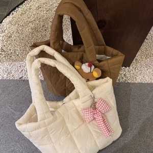 Quilted puffy tote bags in cream and caramel colors with stylish charm accessories