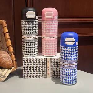 Close-up of houndstooth pattern vacuum flasks in black, pink and blue with latch lid