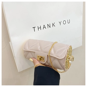 Detail of beige quilted cylindrical bag with golden chain and pearl decoration
