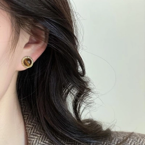 Retro round tiger eye stud earrings with twisted gold frame worn by a female model
