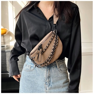 Detail of tan crocodile pattern waist bag featuring layered black metal chains